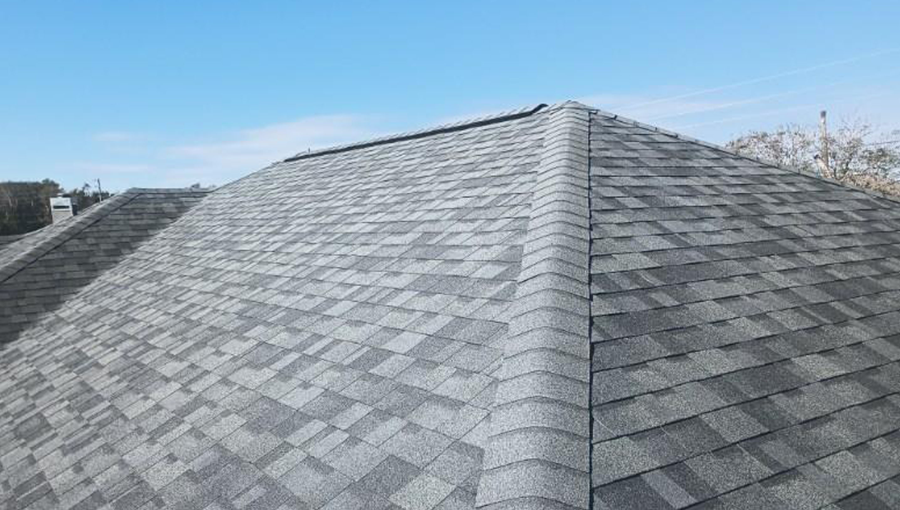 A gray shingled roof with blue sky in the background.