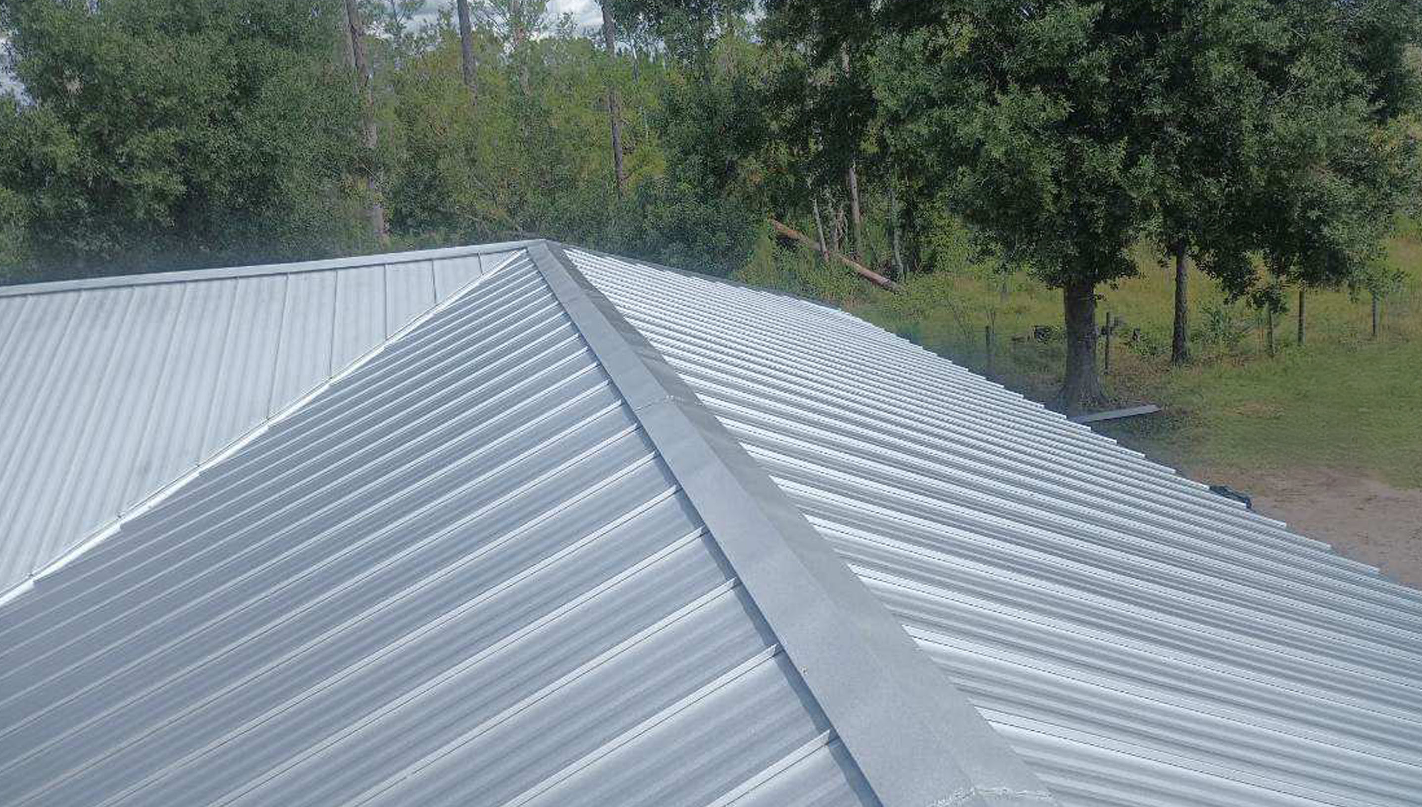 A corrugated metal roof with trees in the background.