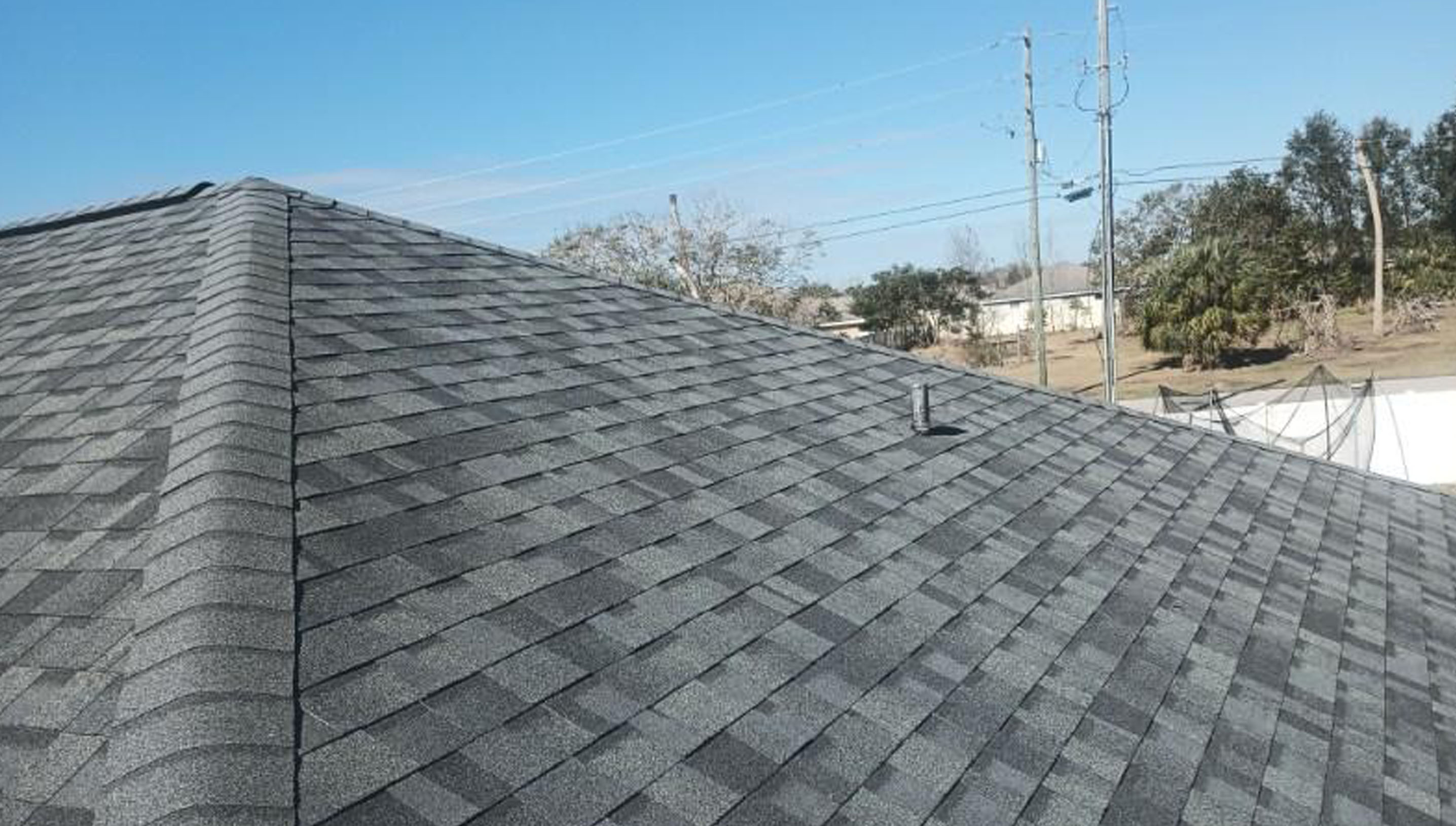 A sloped roof with dark gray asphalt shingles and a small vent pipe.