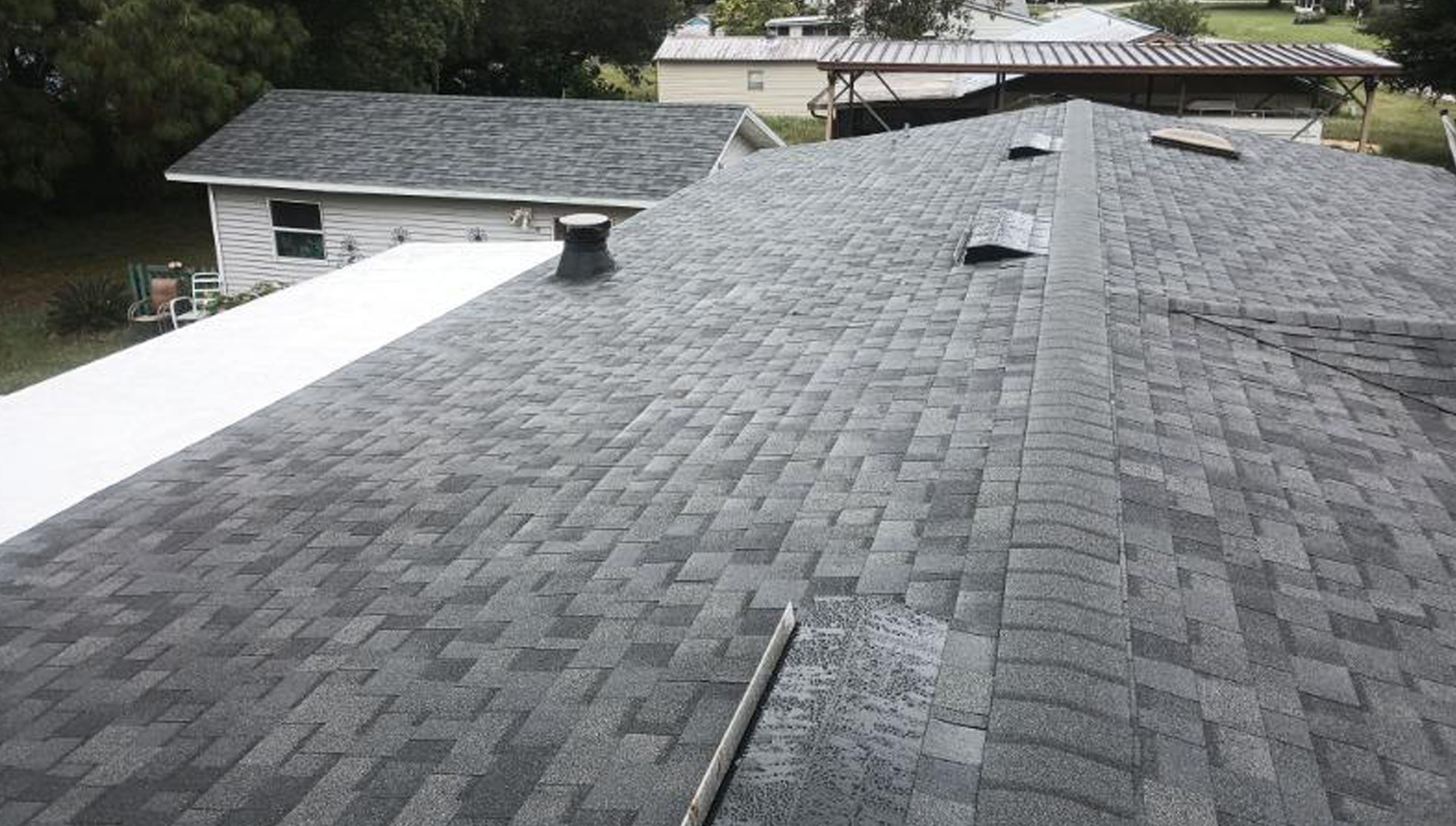 A rooftop with gray asphalt shingles, vents, and a vent pipe.