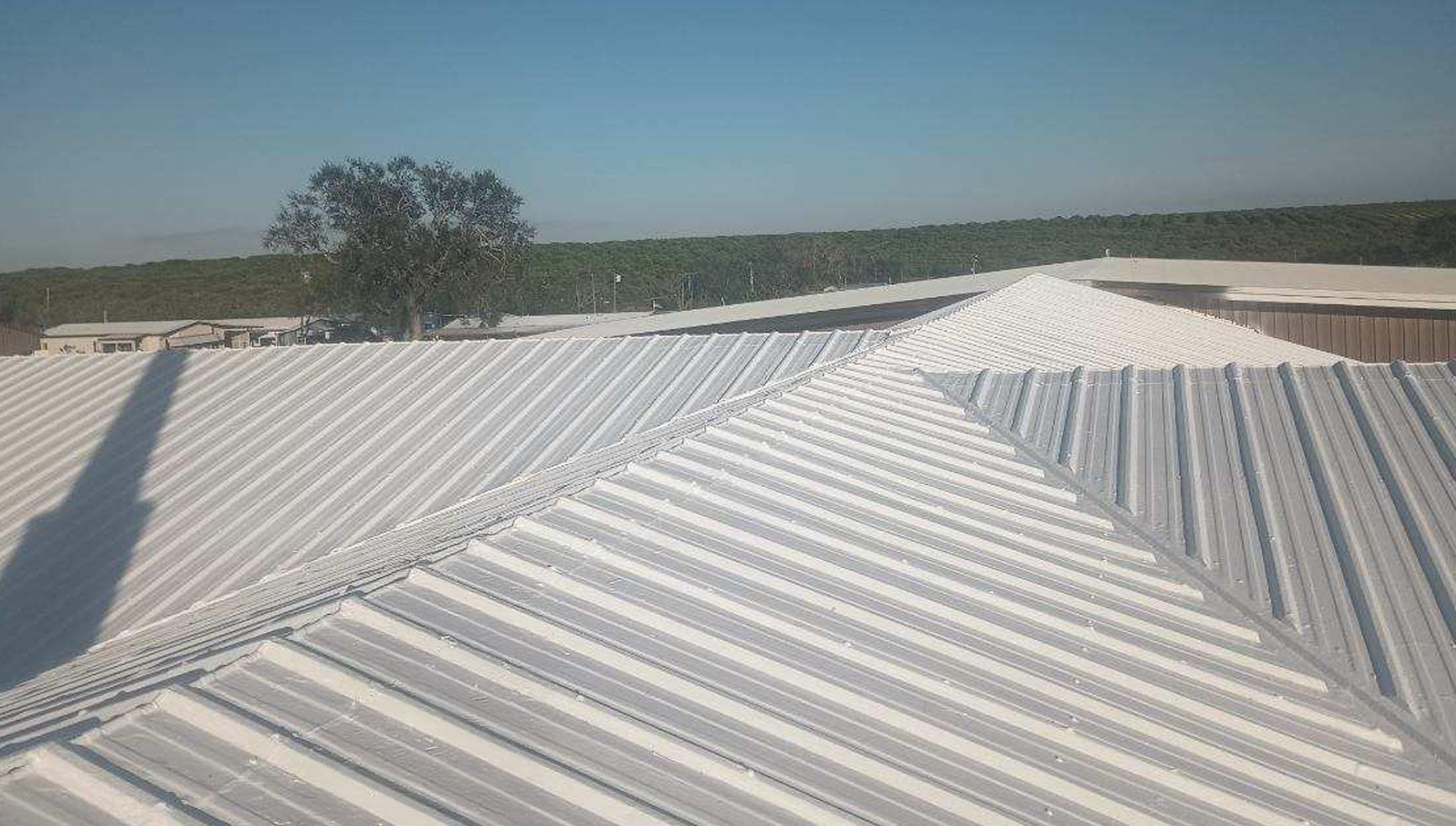 A white corrugated metal roof under a clear blue sky.